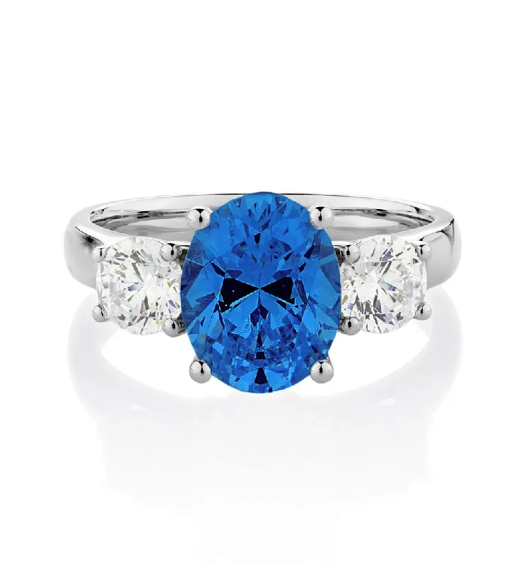 Women’s designer rings-Three stone ring with 10x8mm ceylon sapphire simulant and 0.92 carats* of diamond simulants in 10 carat white gold